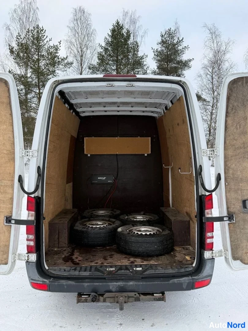 Takaa: Auton takaosalta: takaovet auki, lastitilassa neljä rengas vanteilla, takapuskuri ja rekavetokkeet näkyvissä.