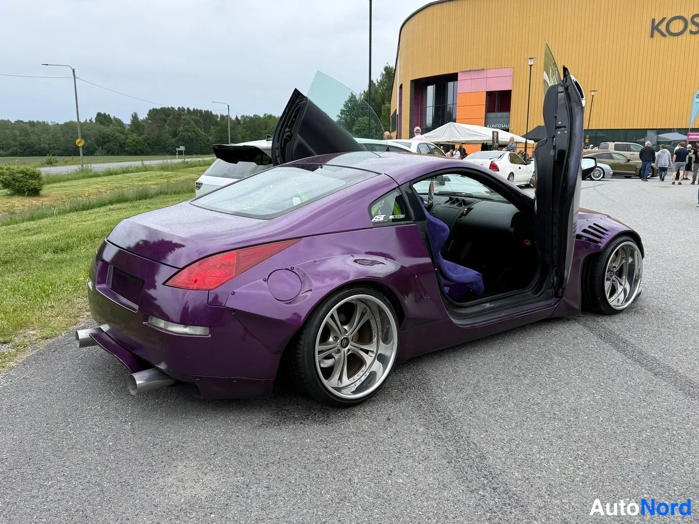 Takaviisto: Violetti coupé takakulmasta: takavalot, kiinni tyhjä tavaratila, molemmat ovet ylhäällä, leveät lokasuojat ja hopeavanteet.