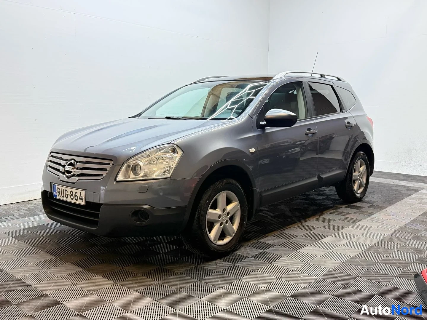 Etuviisto, nokka vasemmalle: Auton etukulmasta otettu kuva: tummanharmaa Nissan Qashqai -maasturi rekisteritunnuksella näkyy keulansa ja vasemman sivupolkensa osalta sisätiloissa r