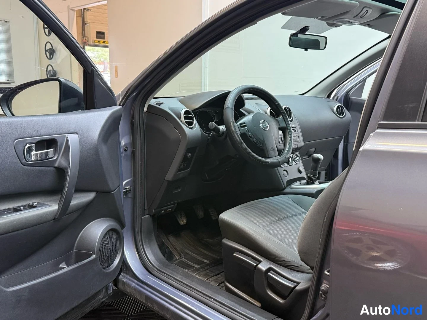 Muu: Auton etusivu auki, näkyvät ohjaamo, ratissa Nissan-logo ja manuaalivaihtehde
