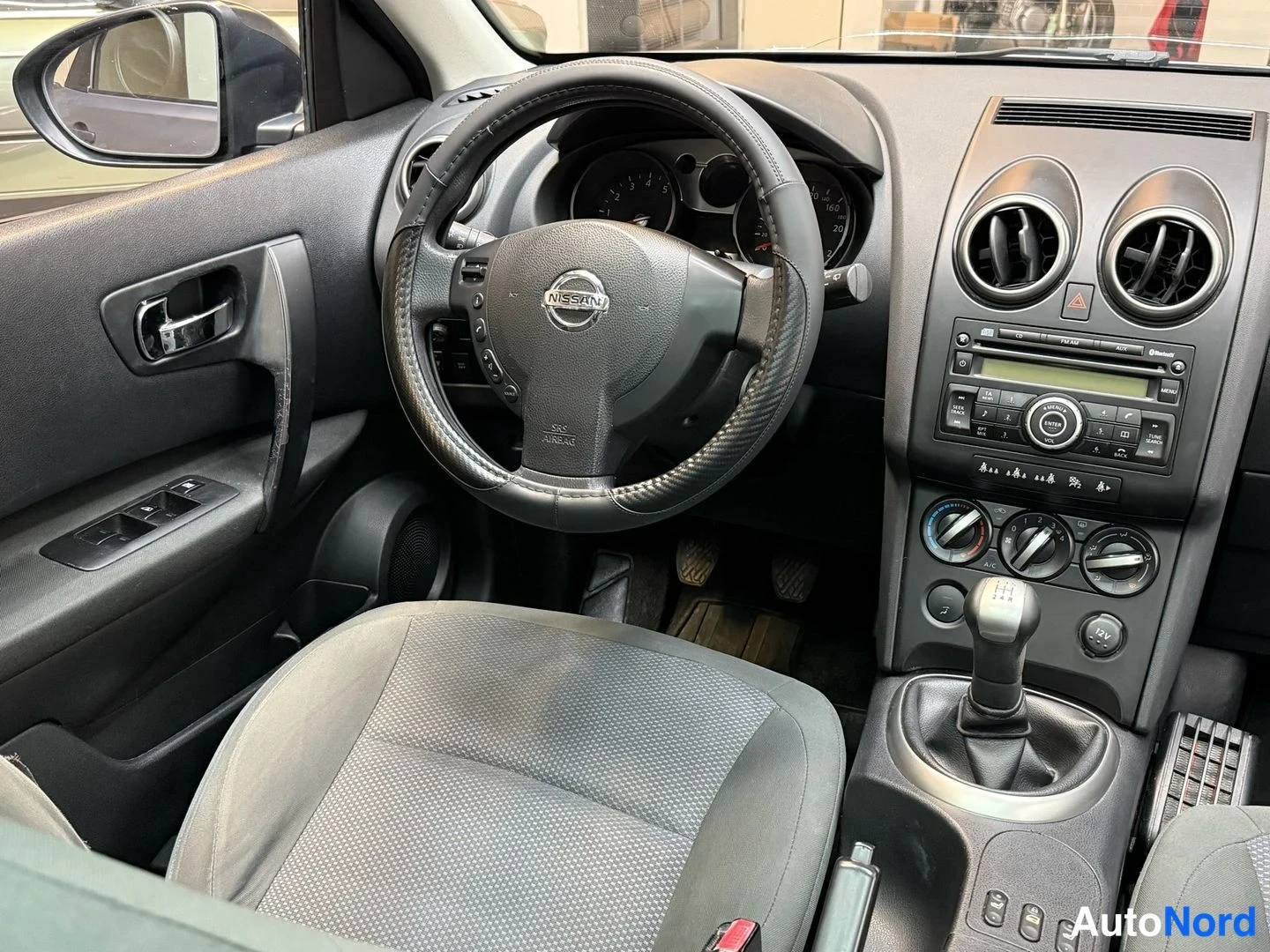 Muu: Ohjaamo vasemmalta: Nissan-ohjauspyörä, käsivalintaan kytketty vaihtokeppi, radio ja ilmastointisäätimet.