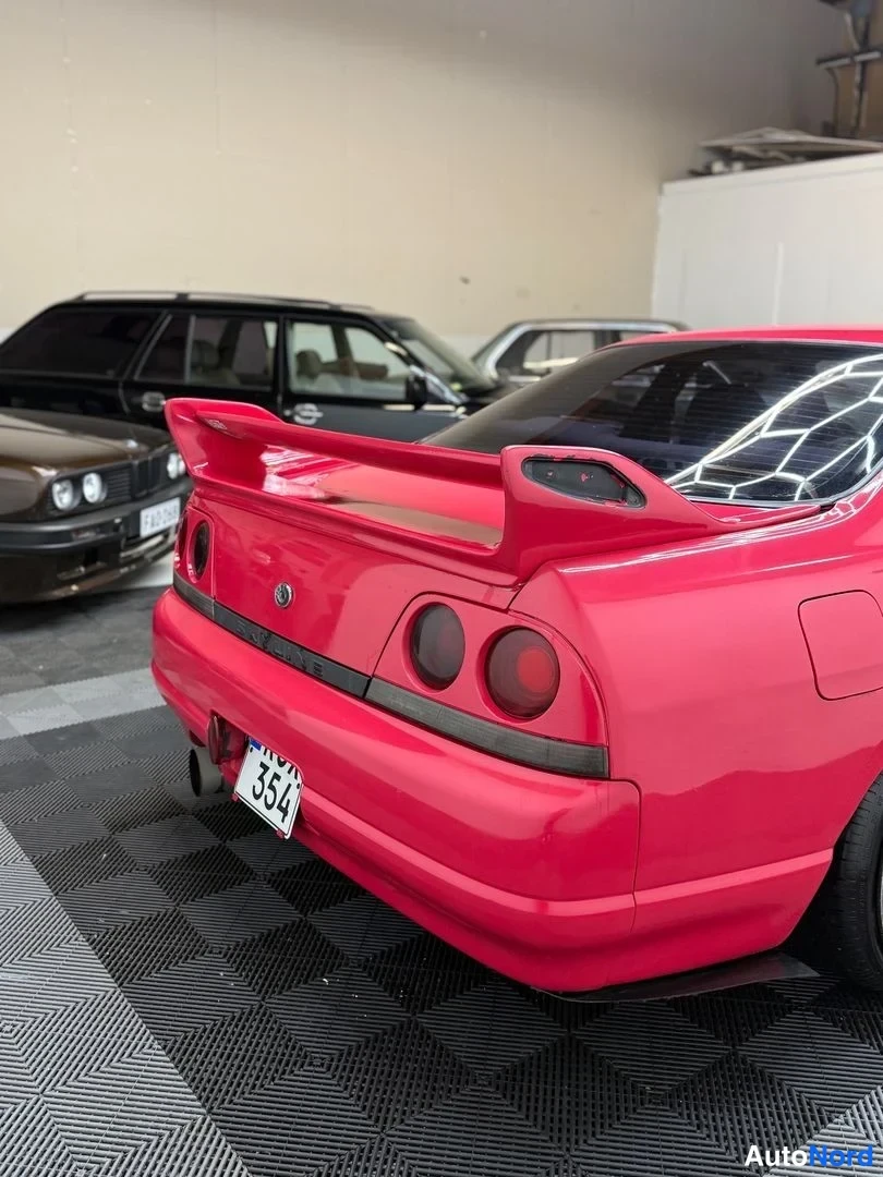 Takaa: Punaisen Nissan Skylinen takaosa, suuri takasiipi ja pyöreät takavalot.