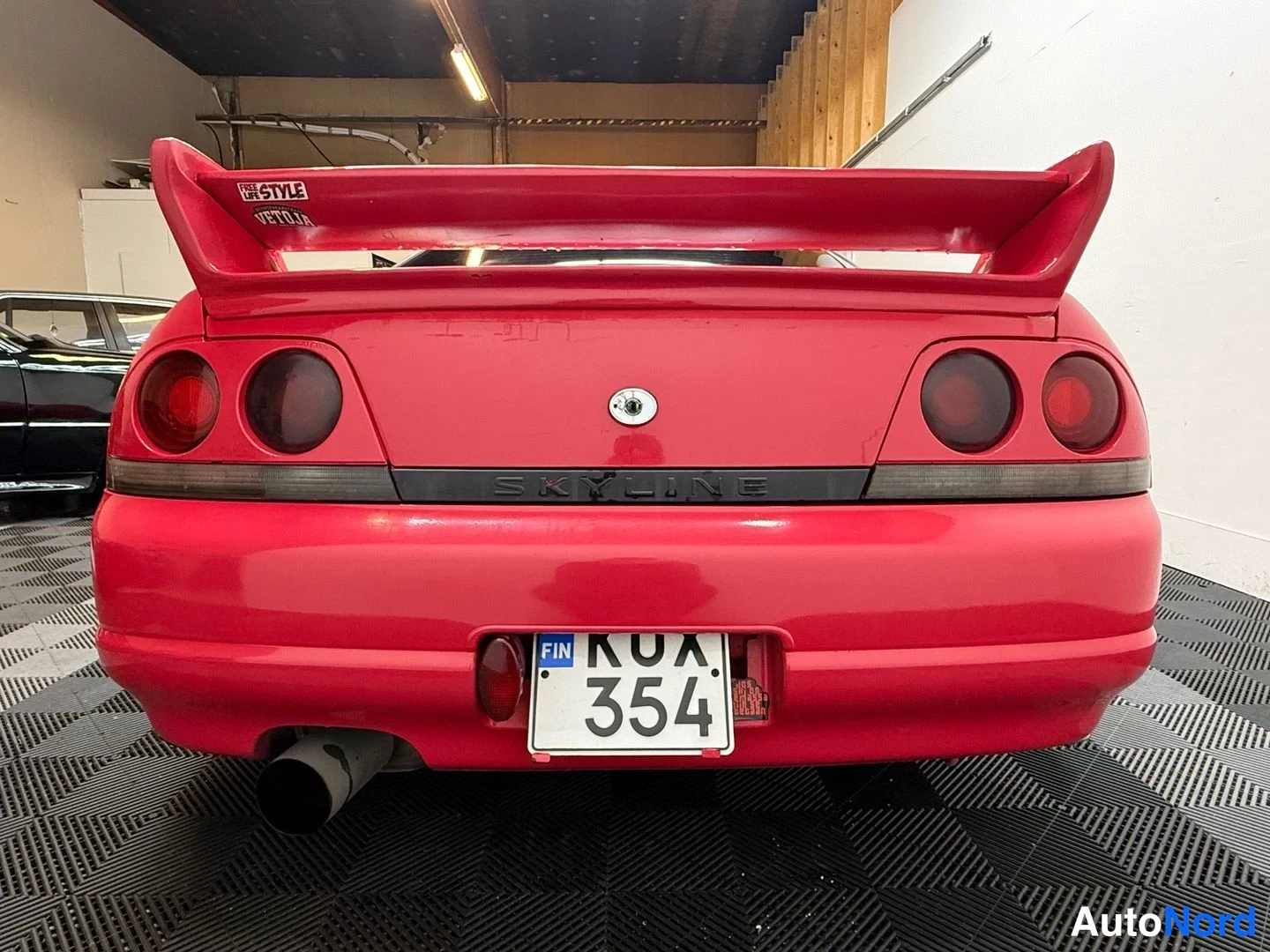Takaa: Punaisen Nissan Skyline -auton takaosa suoraan takaa; rekisterikilpi KUX 354 ja Skyline-teksti näkyvissä.