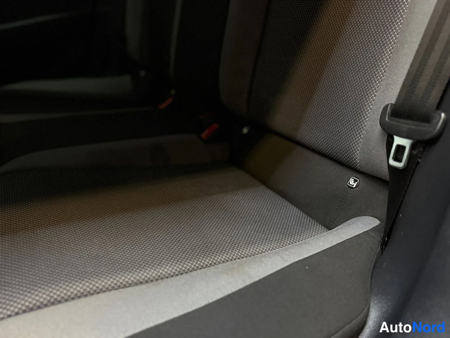 Muu: Lähikuva autossa istuimesta, jossa tumma puuvillakudos ja harmaa istuintyyny; istuimen kyljessä ISOFIX-merkintä ja turvavyö.