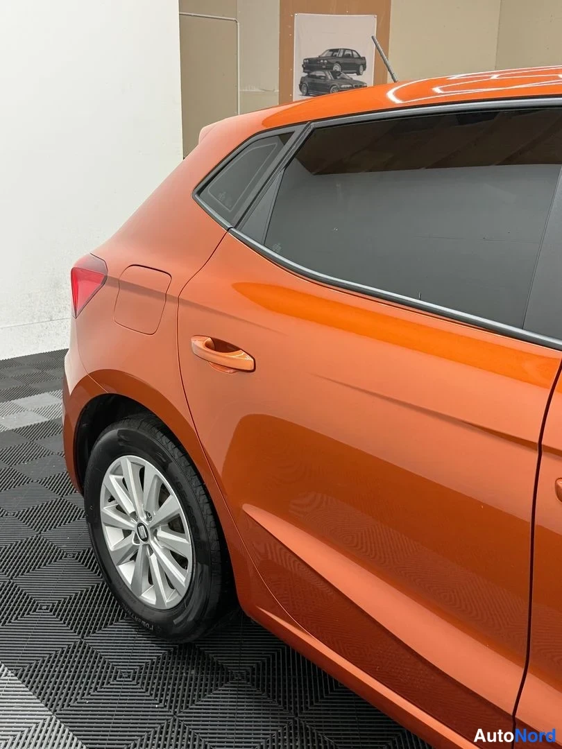 Takaviisto: Oranssin Seat Ibizan takakulma ja vasen kylki kuvattuna sisätiloissa.