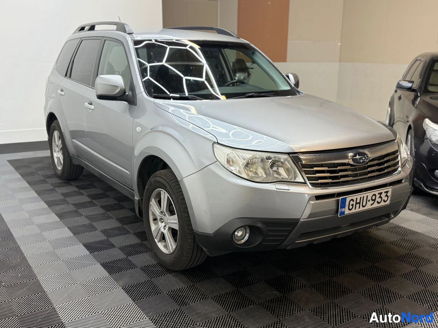 Etuviisto, nokka oikealle: Hopeanharmaa Subaru Forester kolmesta neljästä kulmasta edestä oikealta, rekisterikilpi.