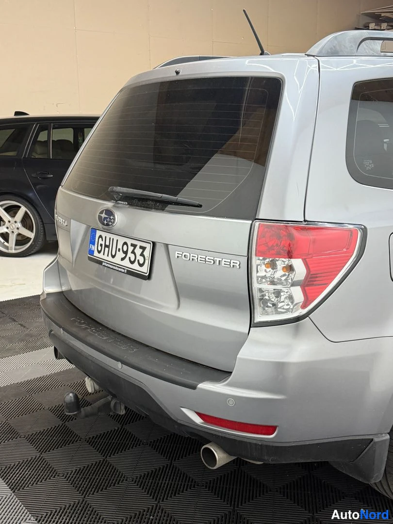Takaa: Lähikuva auton takaa: rekisteritunnus, Subaru-tunnus ja FORESTER-teksti takaluukussa, vetokoukku näkyvissä.