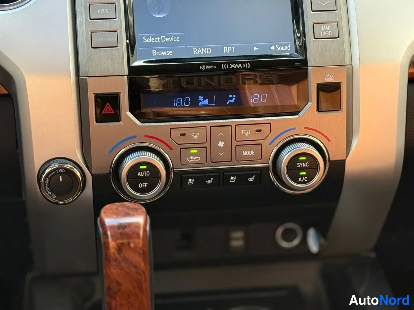 Edestä: Kojelaudan keskusyksikkö lähikuvassa: TUNDRA-teksti, ilmastointinäyttö 18.0 ja nappulat kuten AUTO, OFF, SYNC, A/C.