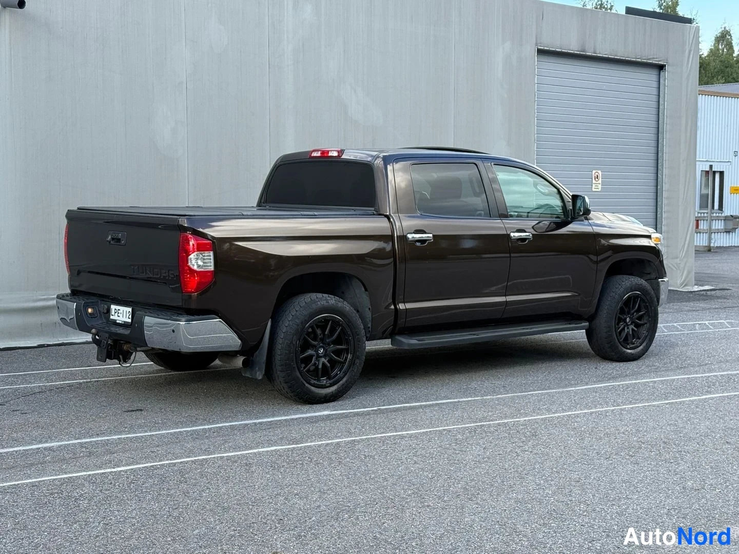Takaviisto: Toyota Tundra -nappikuorma-auto takakolmasosa vasemmalta; tummanruskea kori, kromipuskari ja vetokoukku, rekisteri.