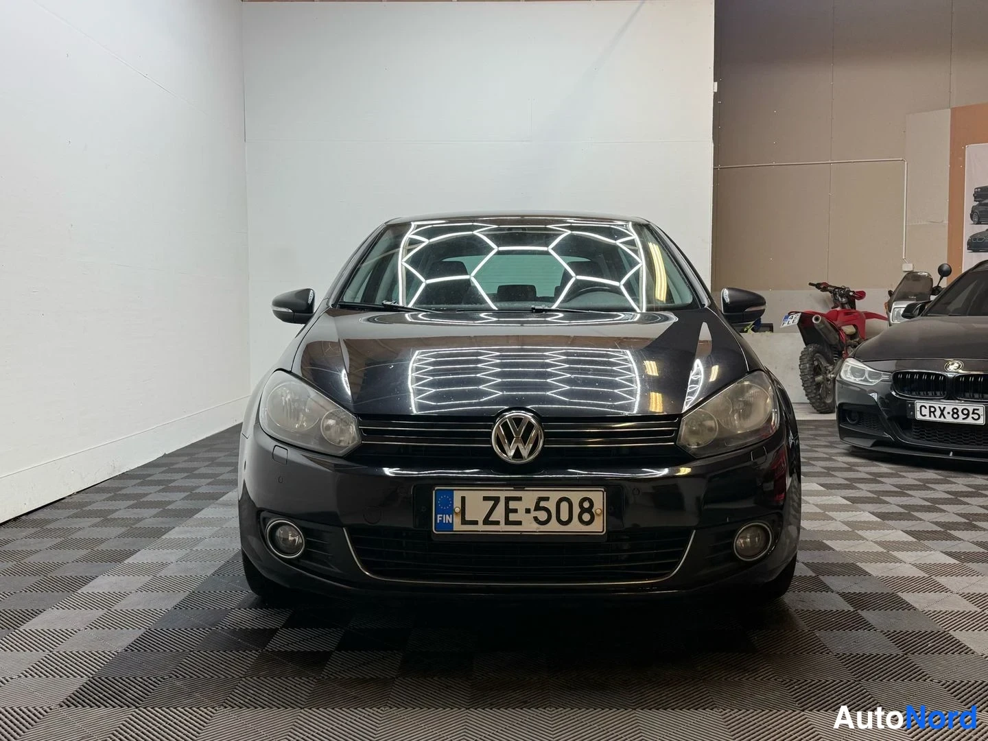 Edestä: Mustan Volkswagen Golfin suora etukuva, rekisterikilpi.