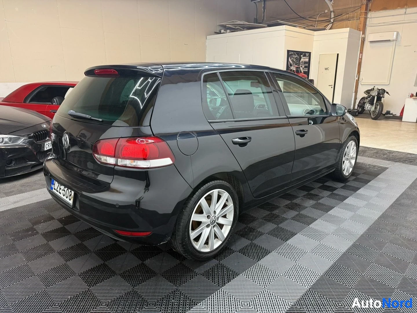 Takaviisto: Mustan Volkswagen Golfin takakulmatarkastus sisätilassa, takakori ja kylki näkyvät.