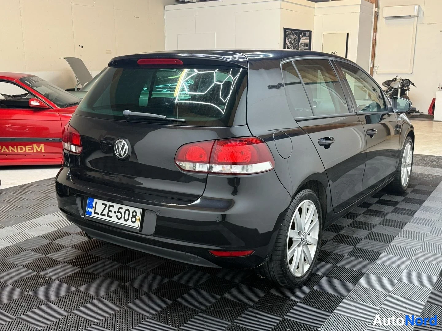Takaviisto: Mustan Volkswagen Golfin takakulmatarkastus sisätilassa, takakori ja kylki näkyvät.