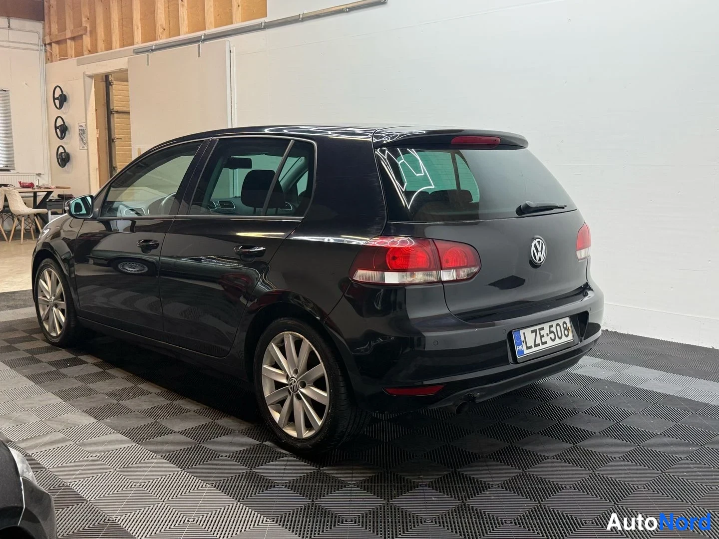 Takaviisto: Mustan Volkswagen Golfin takakulmatarkastus sisätilassa, takakori ja kylki näkyvät.