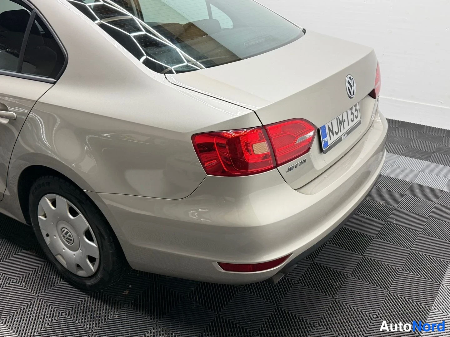 Takaviisto: Volkswagen Jetta -sedanin takaosa ja vasen kylki sivulta ylhäältä kuvattuna; punaiset takavalot, evästetty tavaratilan kansi ja rekisterikilpi näkyvät.