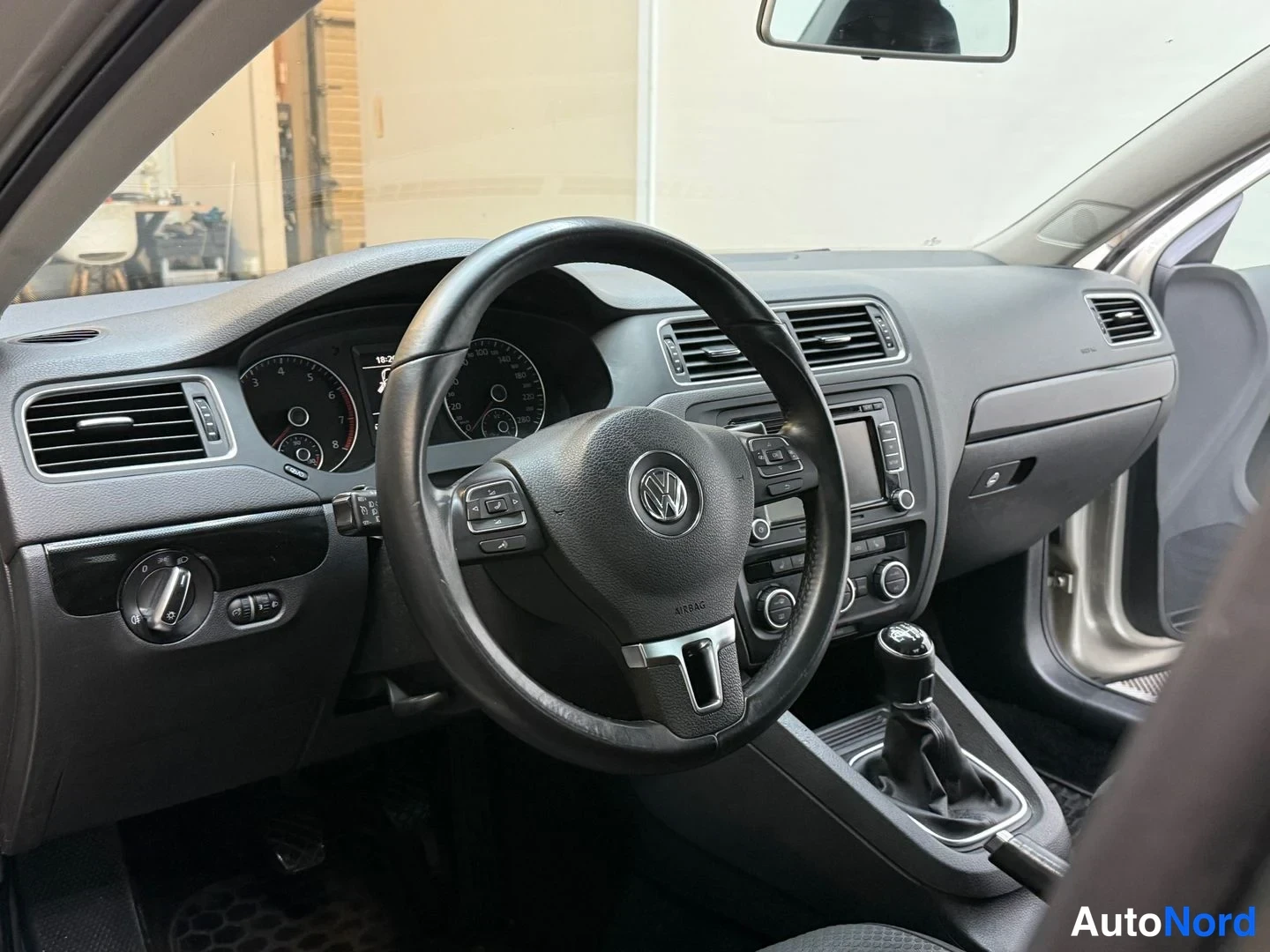 Muu: VW Jetta:n kojelauta ja monitoimiohjauspyörä läheltä kuvattuna; mittaristo, ilmastointisuuttimet ja keskikonsolin radio/kosketusnäyttö näkyvät.