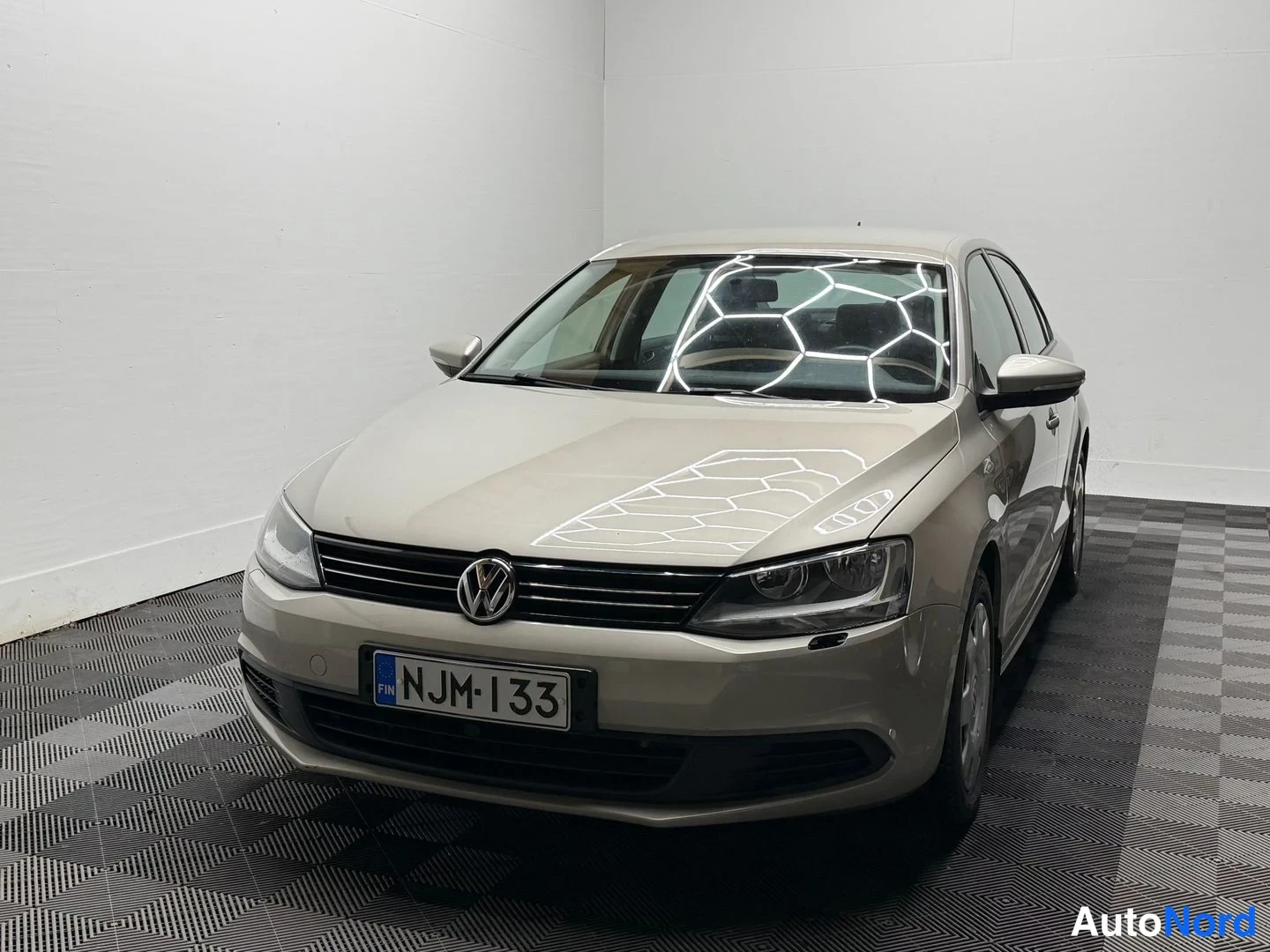 Etuviisto, nokka vasemmalle: Volkswagen Jetta -sedanin suora etukulmanäkymä, vaaleanbeige konepelti ja rekisterikilpi.