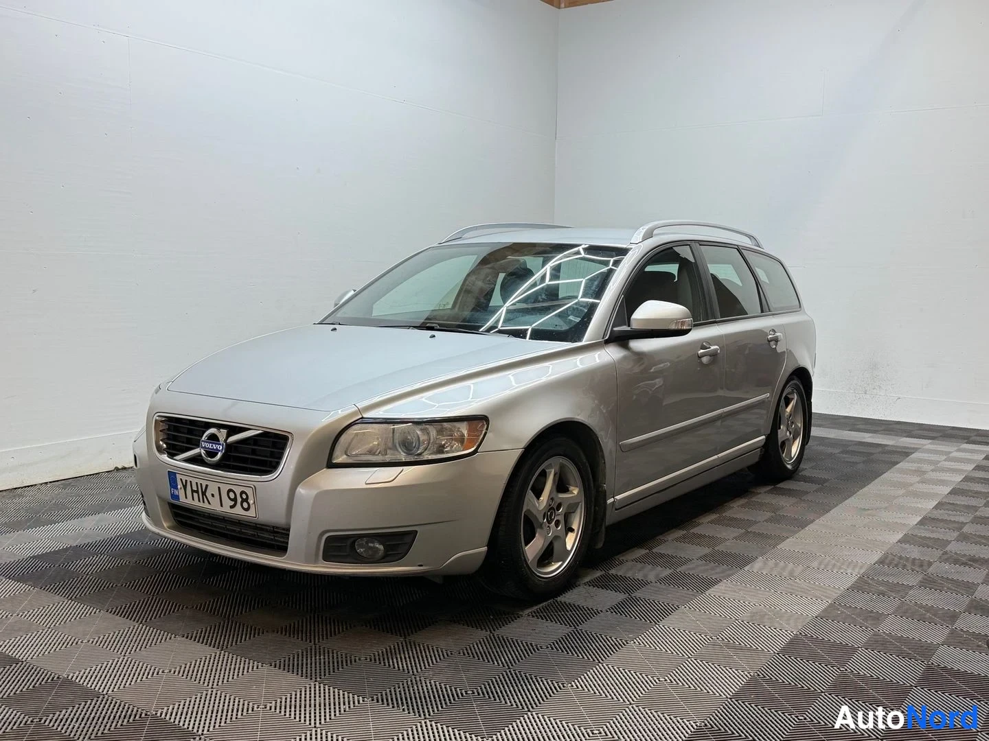 Etuviisto, nokka vasemmalle: Hopeinen Volvo V50 -farmari kulmassa kuvattuna sisätilassa, rekisterikilpi.