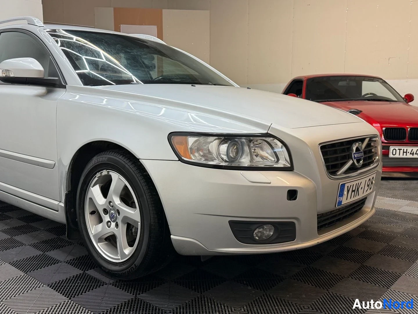 Etuviisto, nokka oikealle: Volvo V50:n keula ja etukylki lähikuvassa, etuvalot ja Volvo-merkki näkyvissä, rekisterikilpi.