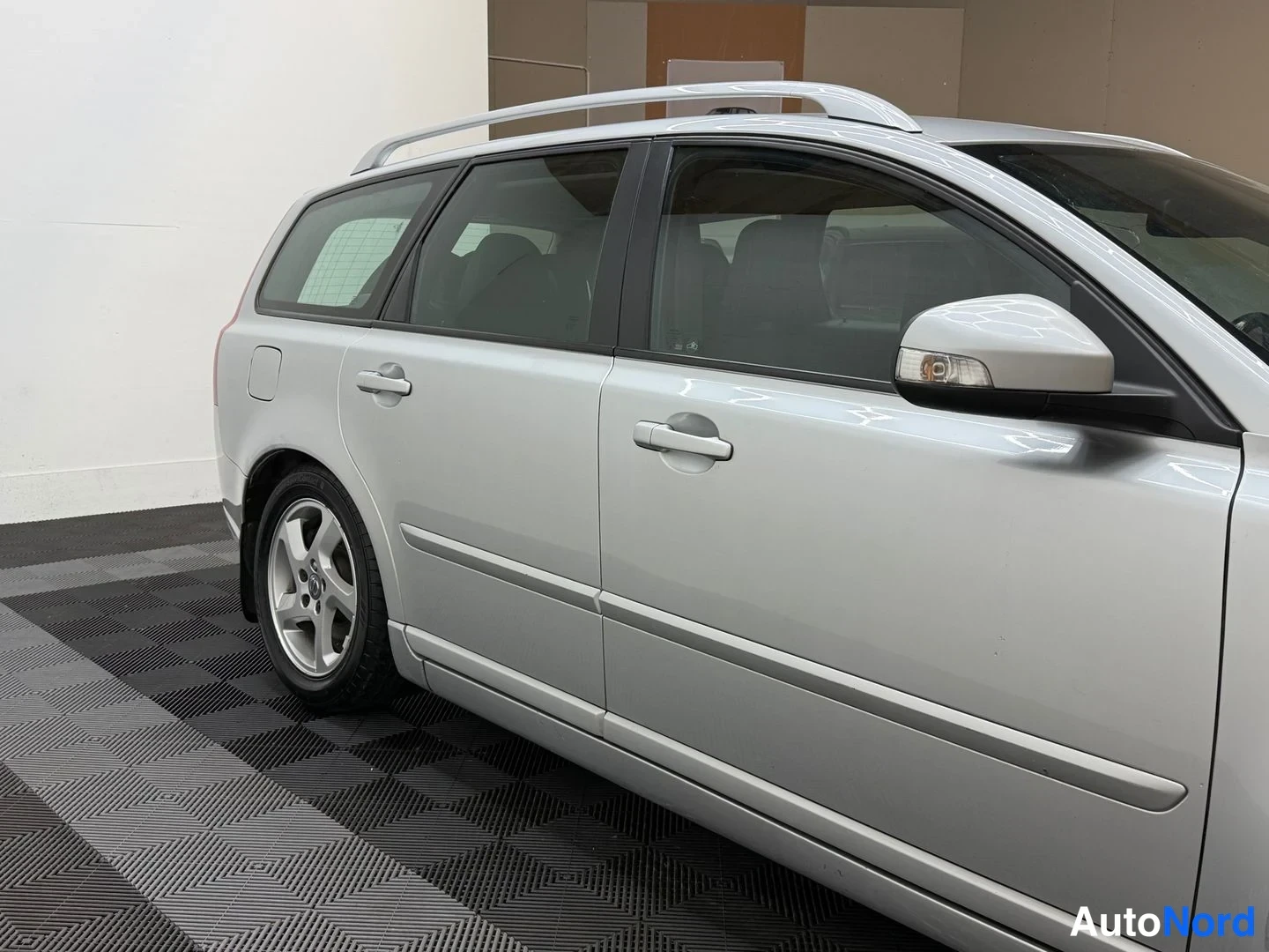 Sivulta: Volvo V50 -farmarin vasen kylki sivulta, kattokaiteet ja ovien kahvat näkyvissä.
