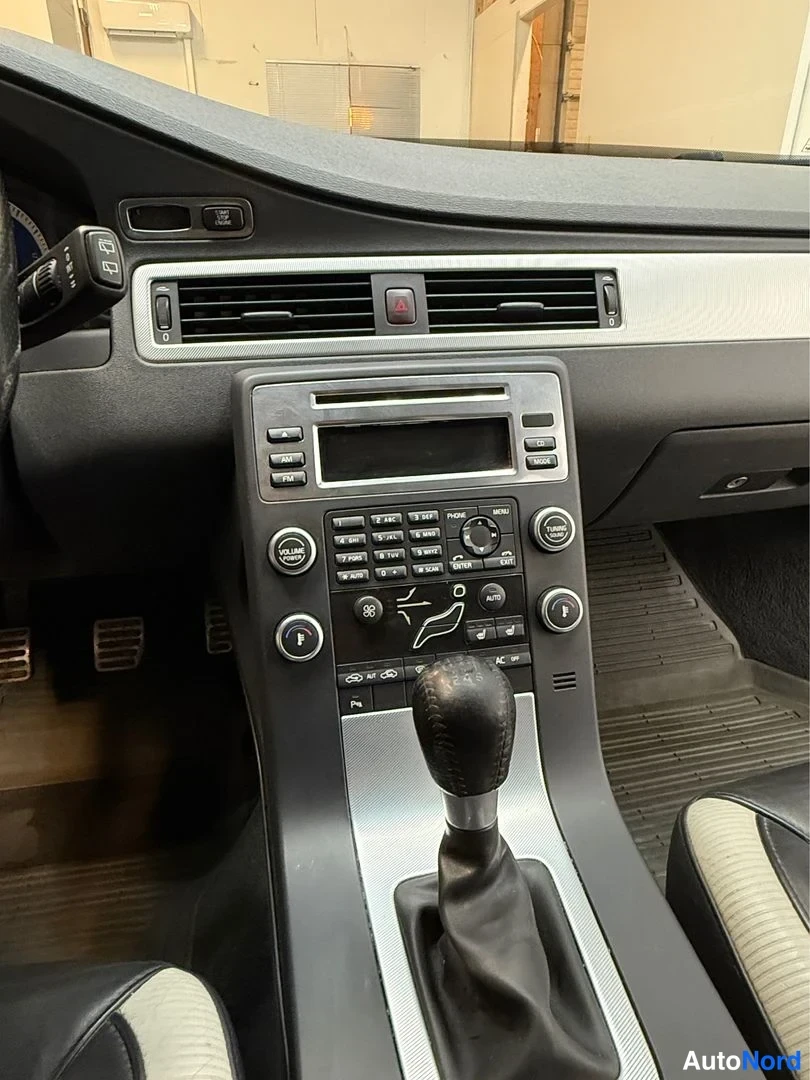 Muu: Keskikonsolin kuva: radio- ja automaattiilmastointipainikkeet, vaihtajan kupi ja kaksivärinen suuristuoli näkyvät.