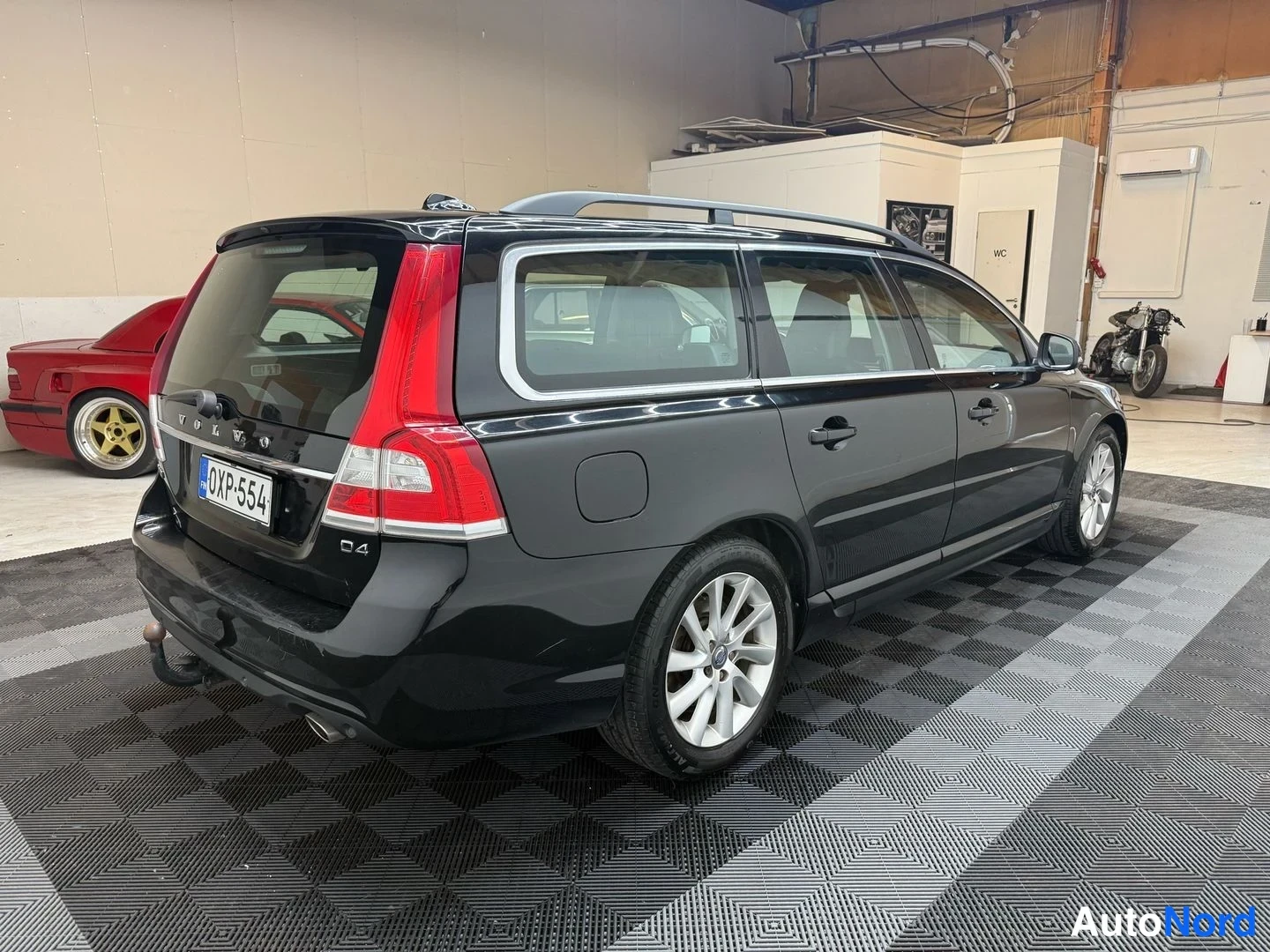 Takaviisto: Mustan farmariauton takakolmannes kuvattuna sisätiloissa, rekisterikilpi, peräluukussa VOLVO- ja D4-tekstit.