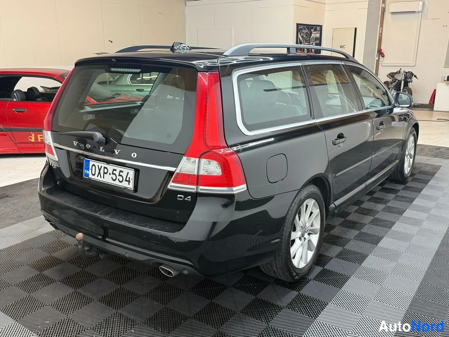 Takaviisto: Mustan farmariauton takakolmannes kuvattuna sisätiloissa, rekisterikilpi, peräluukussa VOLVO- ja D4-merkinnät.
