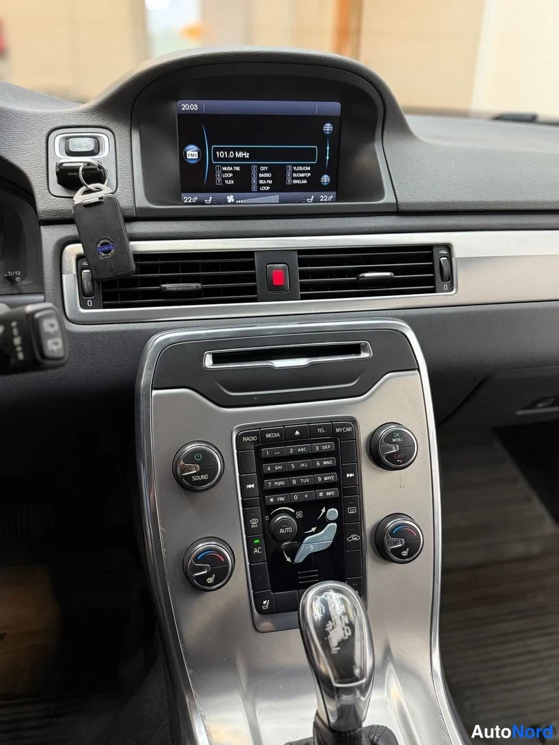 Muu: Volvo V70:n keskitaso suoraan edestä: näyttö radiotiedoin, ilmastointi- ja monenlaiset painikkeet ja automaattivaihteen valitsin.
