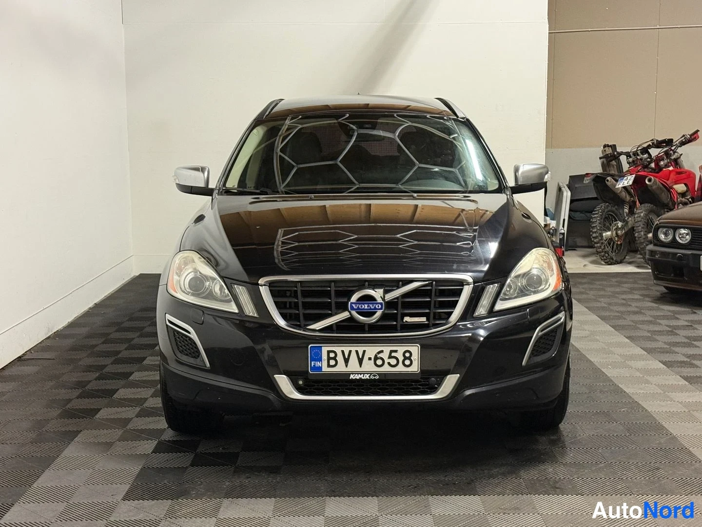 Edestä: Mustan Volvo XC60:n etukuva suoraan edestä sisätiloissa.