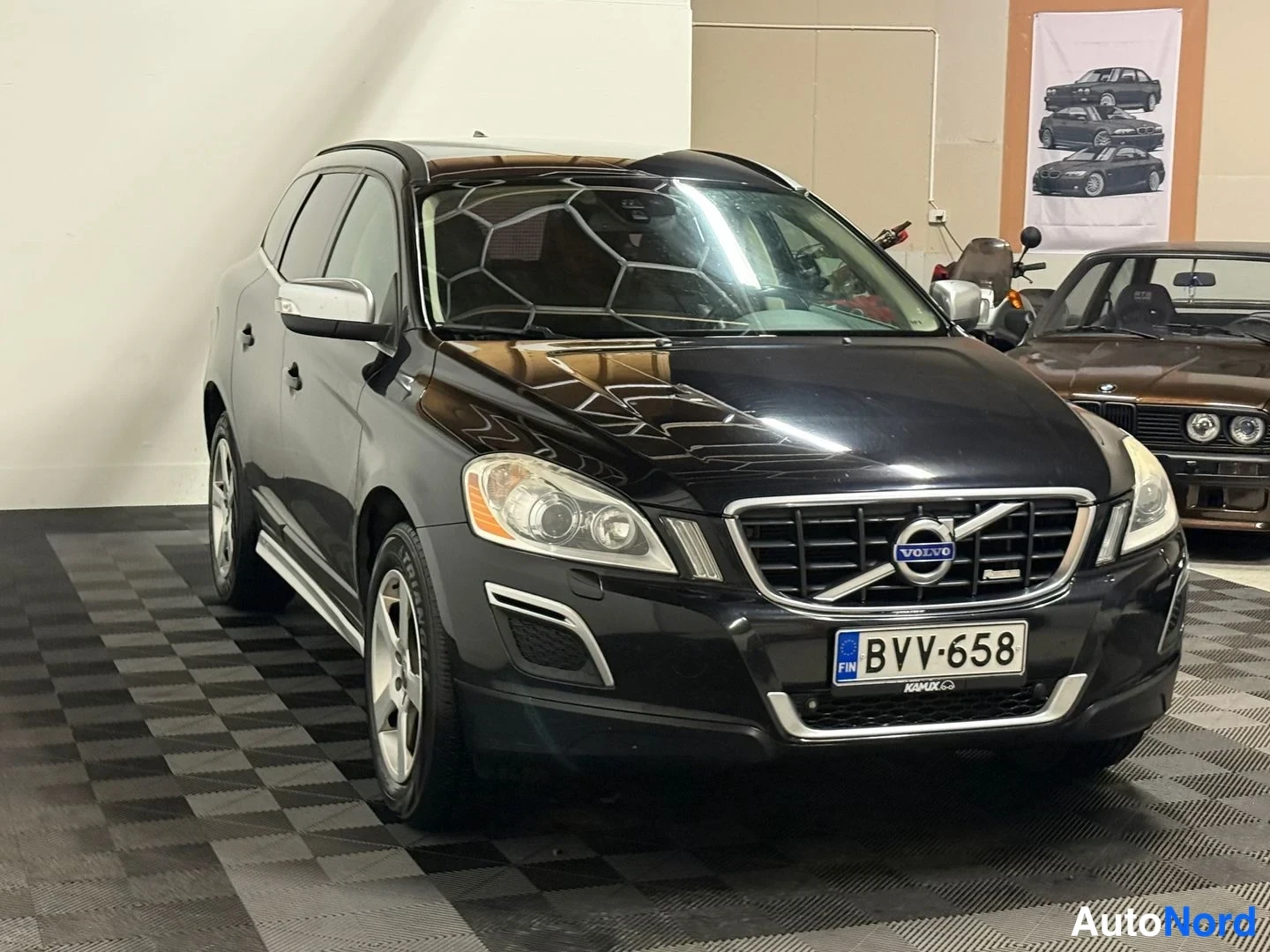Etuviisto, nokka oikealle: Mustan Volvo XC60:n etu-kolmasosakuva sisätiloissa, keula oikealla.