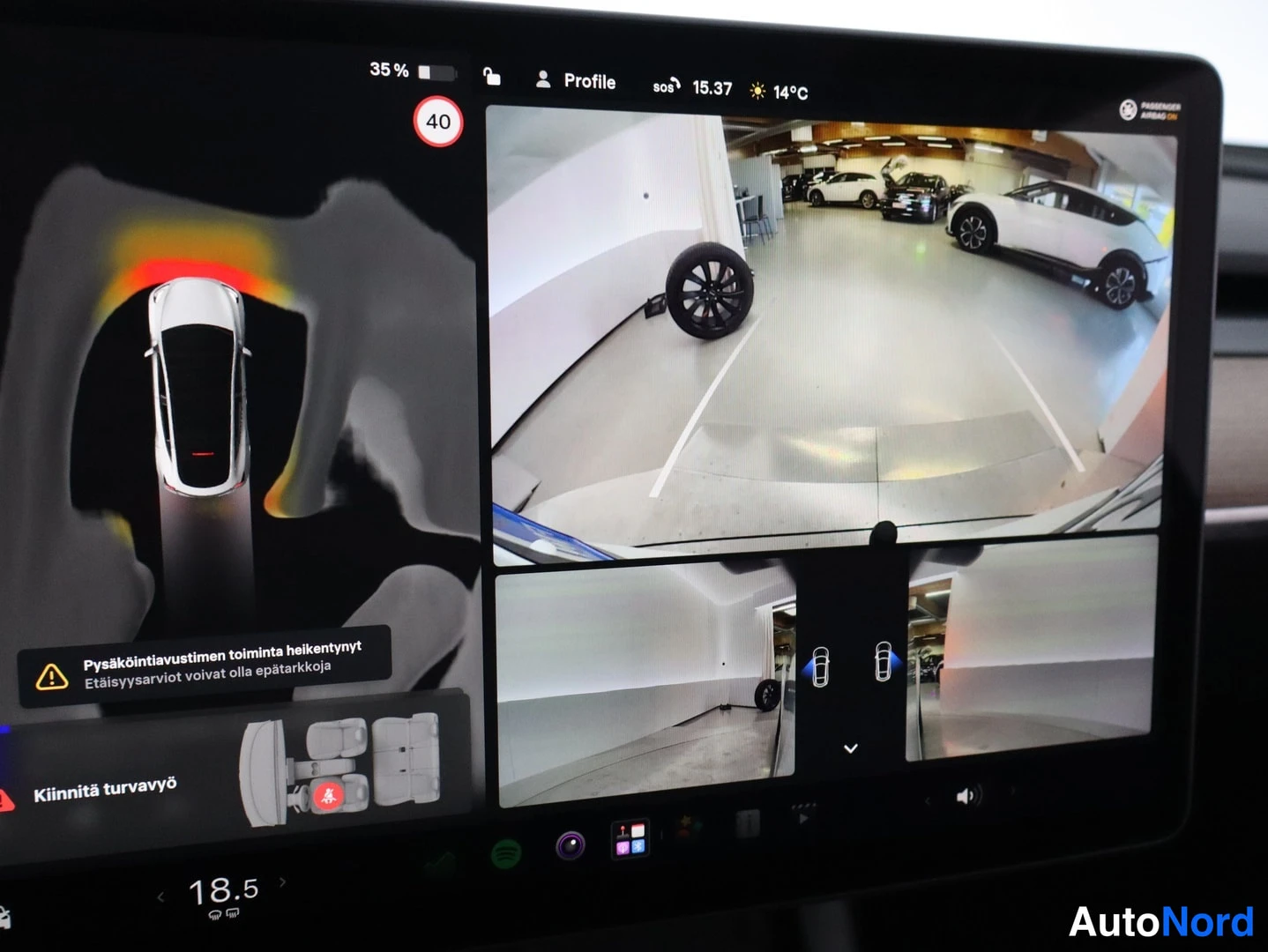 Muu: Tesla-mallin keskinäytön tarkennusnäkymä: lähitunnistusvaroitus, 360-kamerakuva autotallista ja etäisyysvaroituksia.