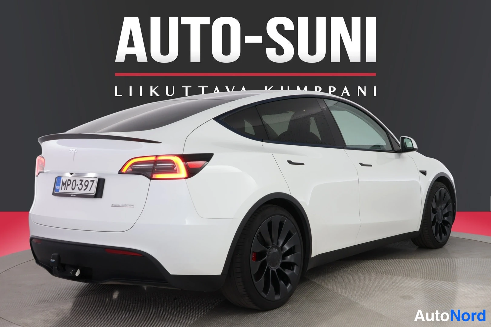 Takaviisto: Valkoinen Tesla Model Y taka-kulmanäkymässä, rekisteritunnus MP0-397, perävetokoukku näkyvissä.