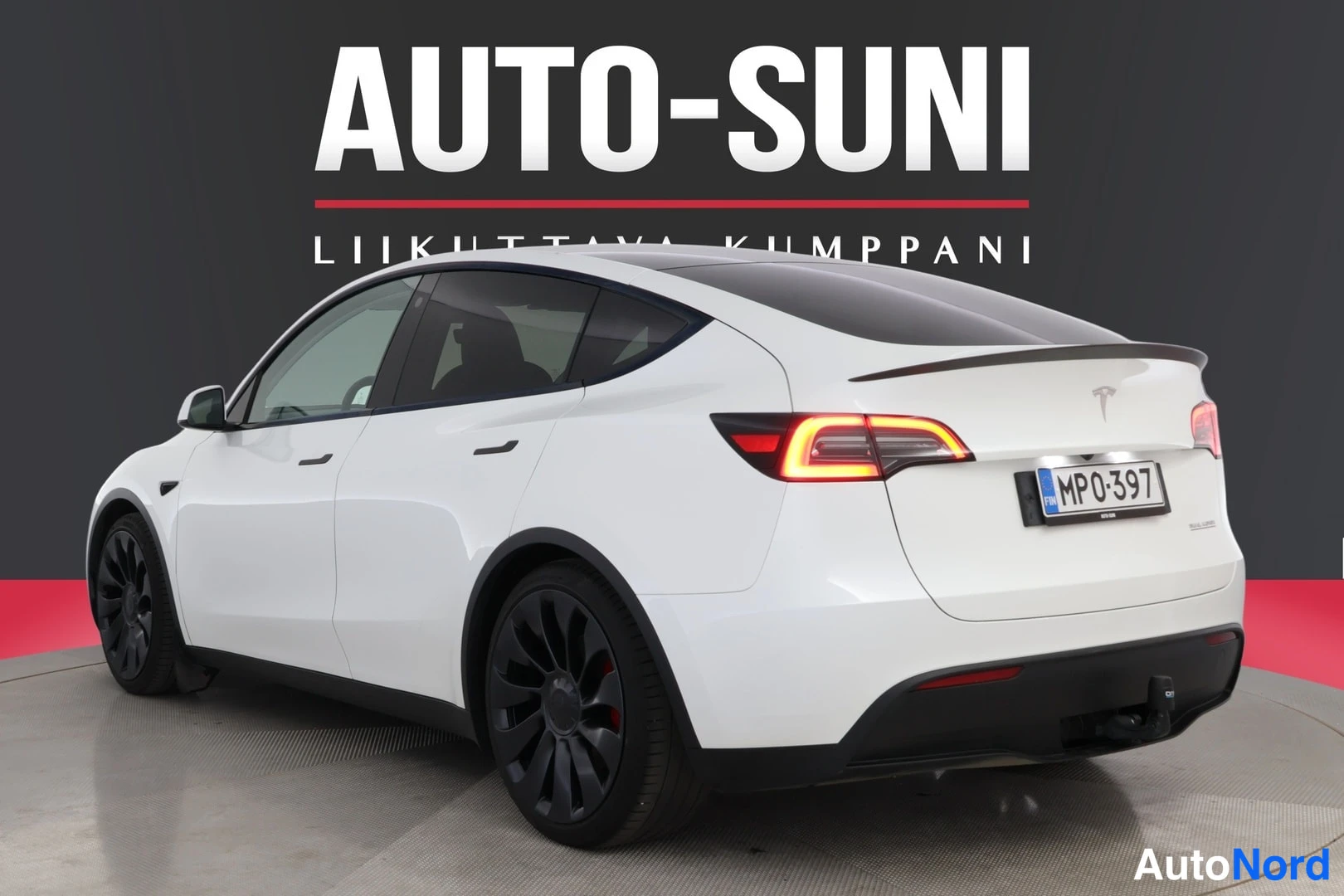 Takaviisto: Valkoinen Tesla Model Y takaa sivusuunnassa kuvattuna, rekisteritunnus MP0-397, takavalo syttyneenä.