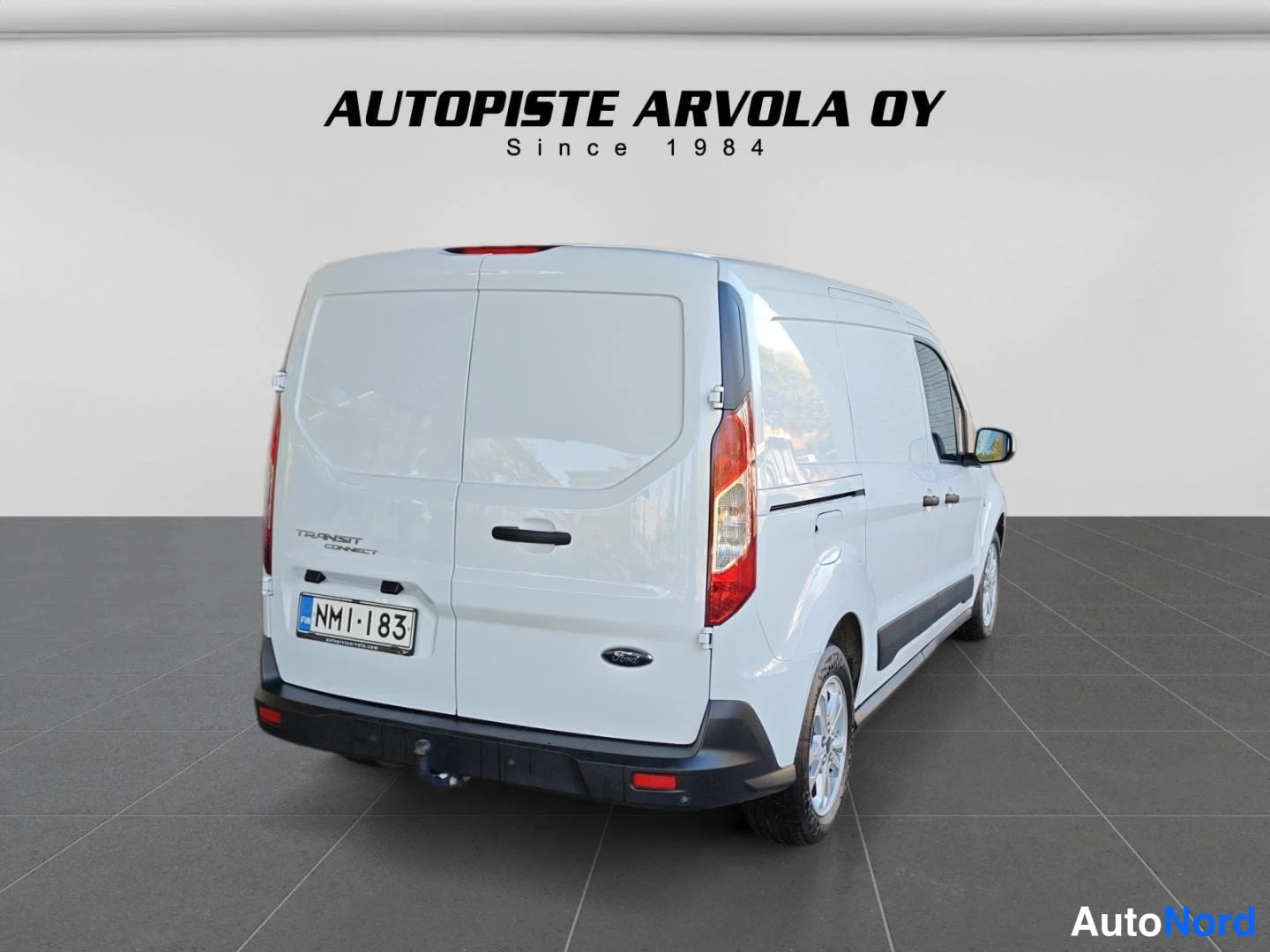 Takaa: Valkoisen Ford Transit Connect -pakettiauton takaosa suoraan takaa, rekisterikilpi ja Ford-merkki näkyvissä.