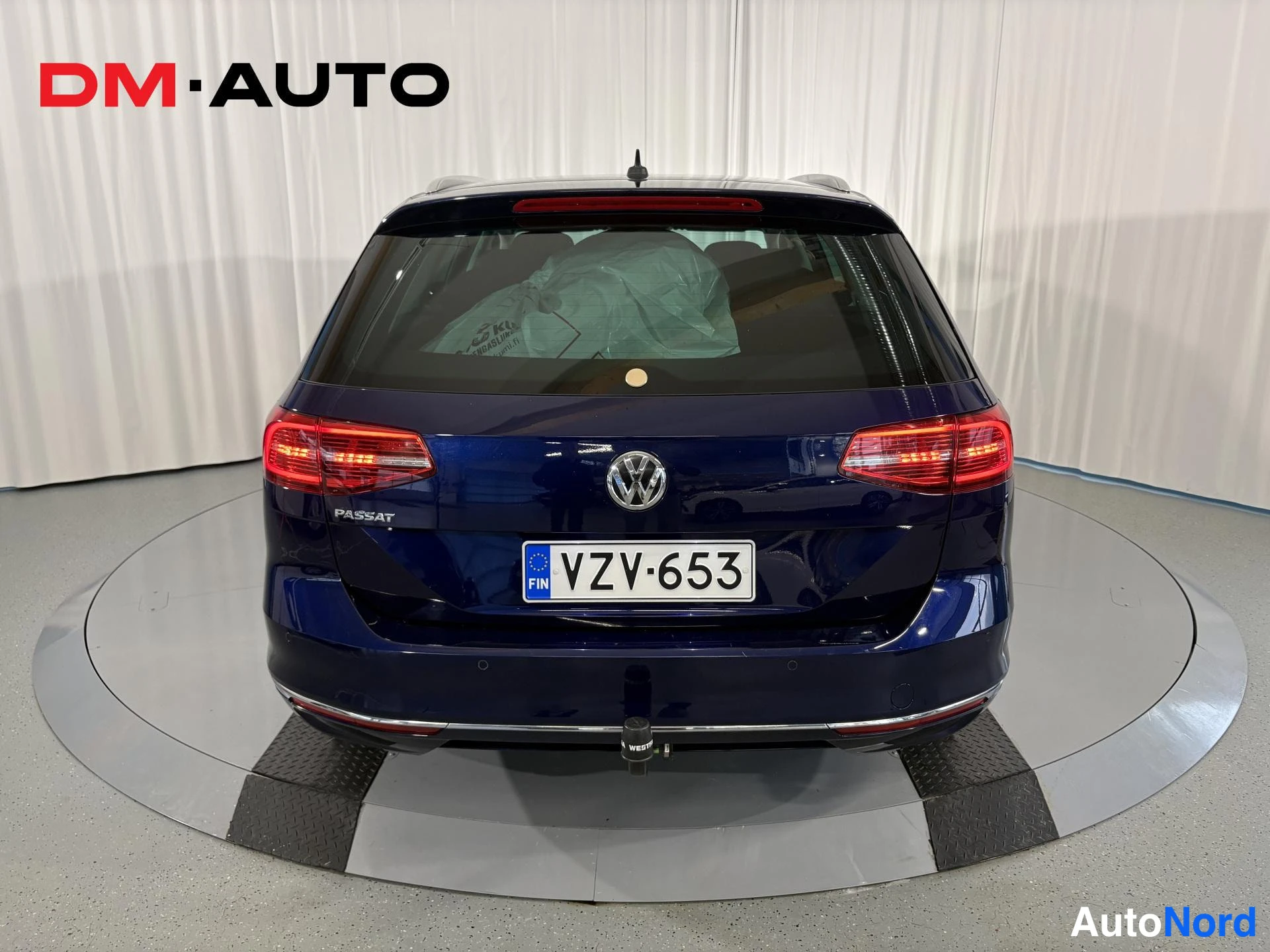 Takaa: Sininen farmariauto suoraan takaa; rekisteritunnus ja PYSÄHDYS/valot päällä takavalot.