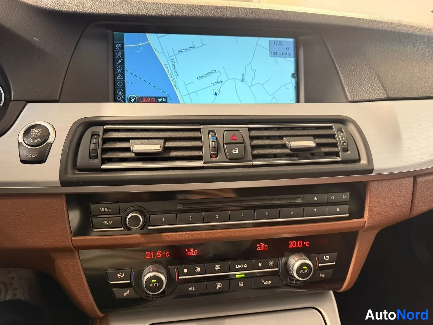 Muu: Kojelaudan keskiosa: näytössä navigaatiokartta, alla ilmastointiautomaatin AUTOnupit, lämpötilat 21,5 °C ja 20,0 °C, sekä radio- ja CD-paneeli.