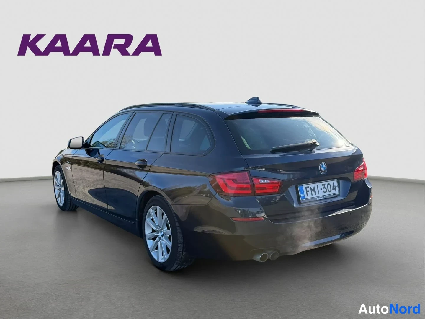 Takaviisto: Auton takakulma: tummansininen BMW-farmari, rekisterikilpi näkyvissä, takavalot ja kattokaari picutuksessa.