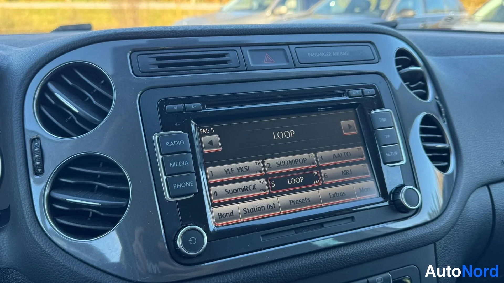 Muu: Kojelaudan keskiyksikön lähikuva: kosketusnäytöllä radio FM 5, kanavavalikko (YLE YKKönen, SUOMIPOP, AALTO, SuomiRCK, LOOP, NRJ), napit RADIO, MEDIA ja PHONE se