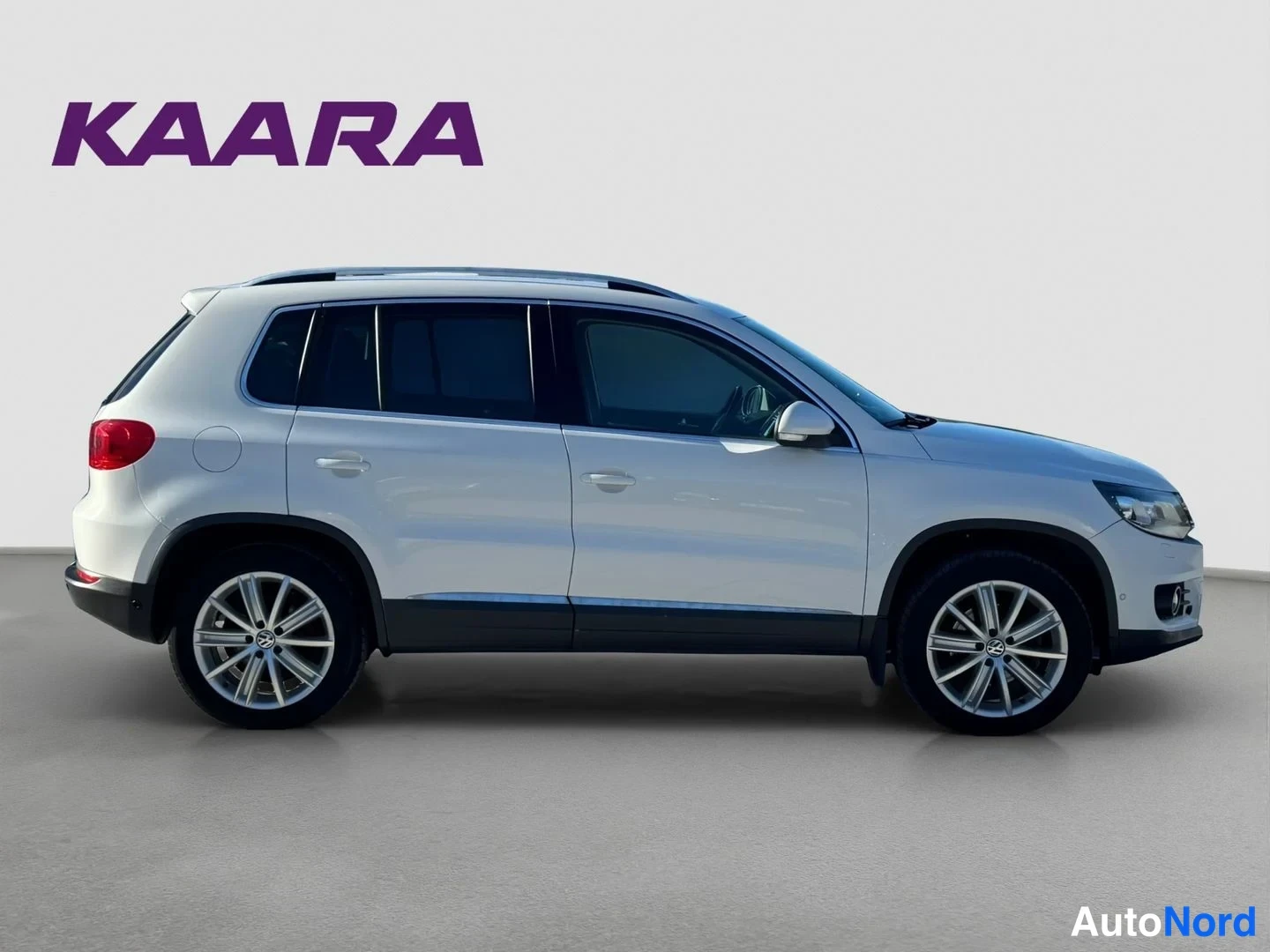 Sivulta: Valkoinen Volkswagen Tiguan sivulta, rekisterikilpi osittain näkyvissä