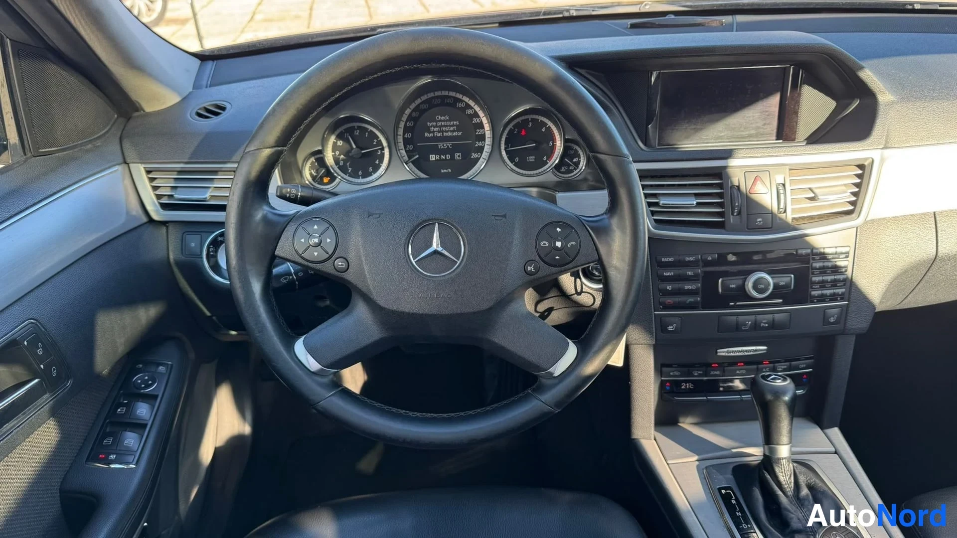 Yksityiskohta: Kuljettajan puolen näkymä ohjaamoon: Mercedes-ohjauspyörä, mittaristo, keskikonsoli ja automaattivaihteen valitsin.