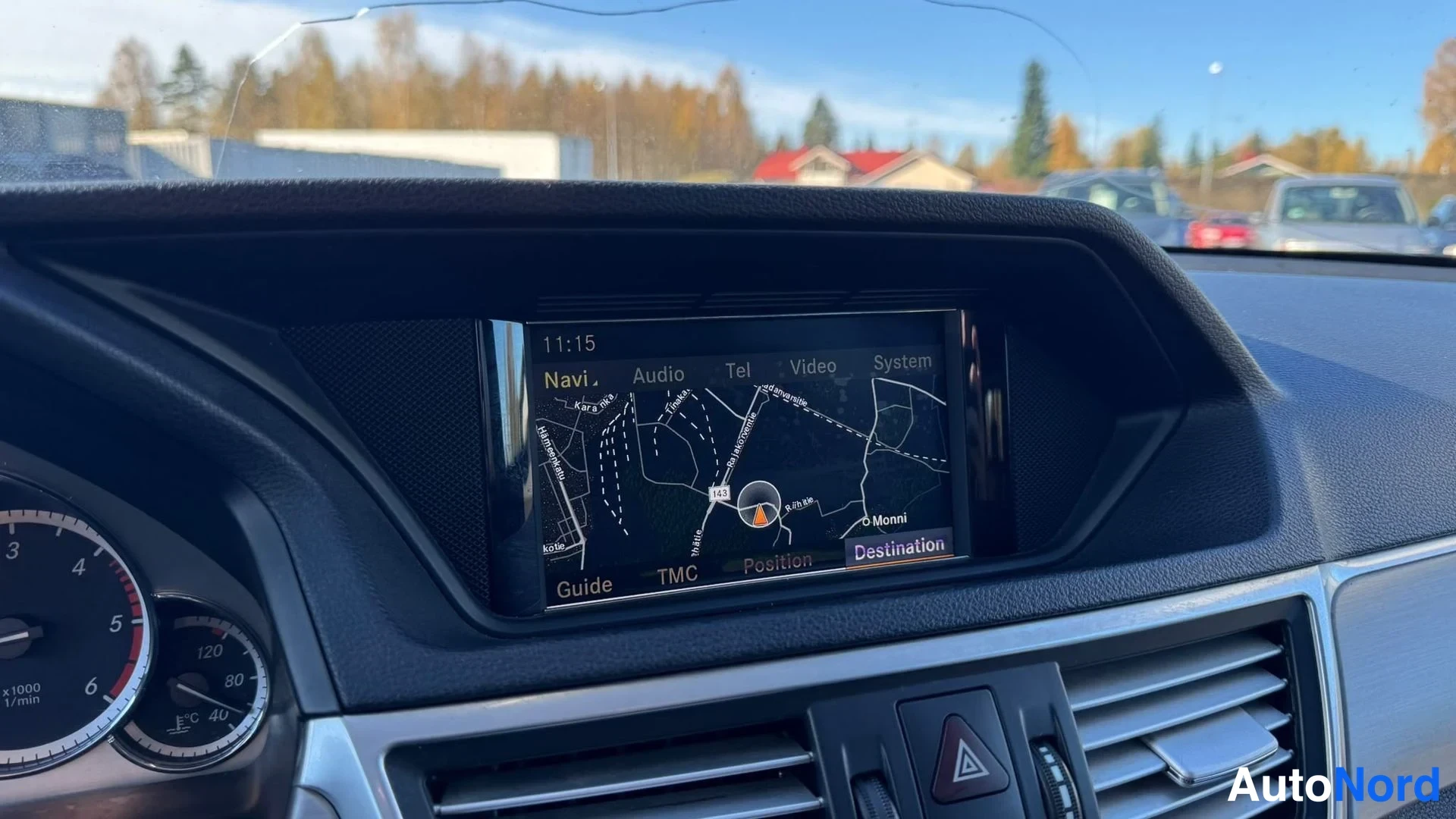 Yksityiskohta: Kojelaudan navigointinäyttä, jolla näkyy kartta ja valikko Navi, Audio, Tel, Video, System. Kellonaika 11:15 ja ikkunassa halkeama.