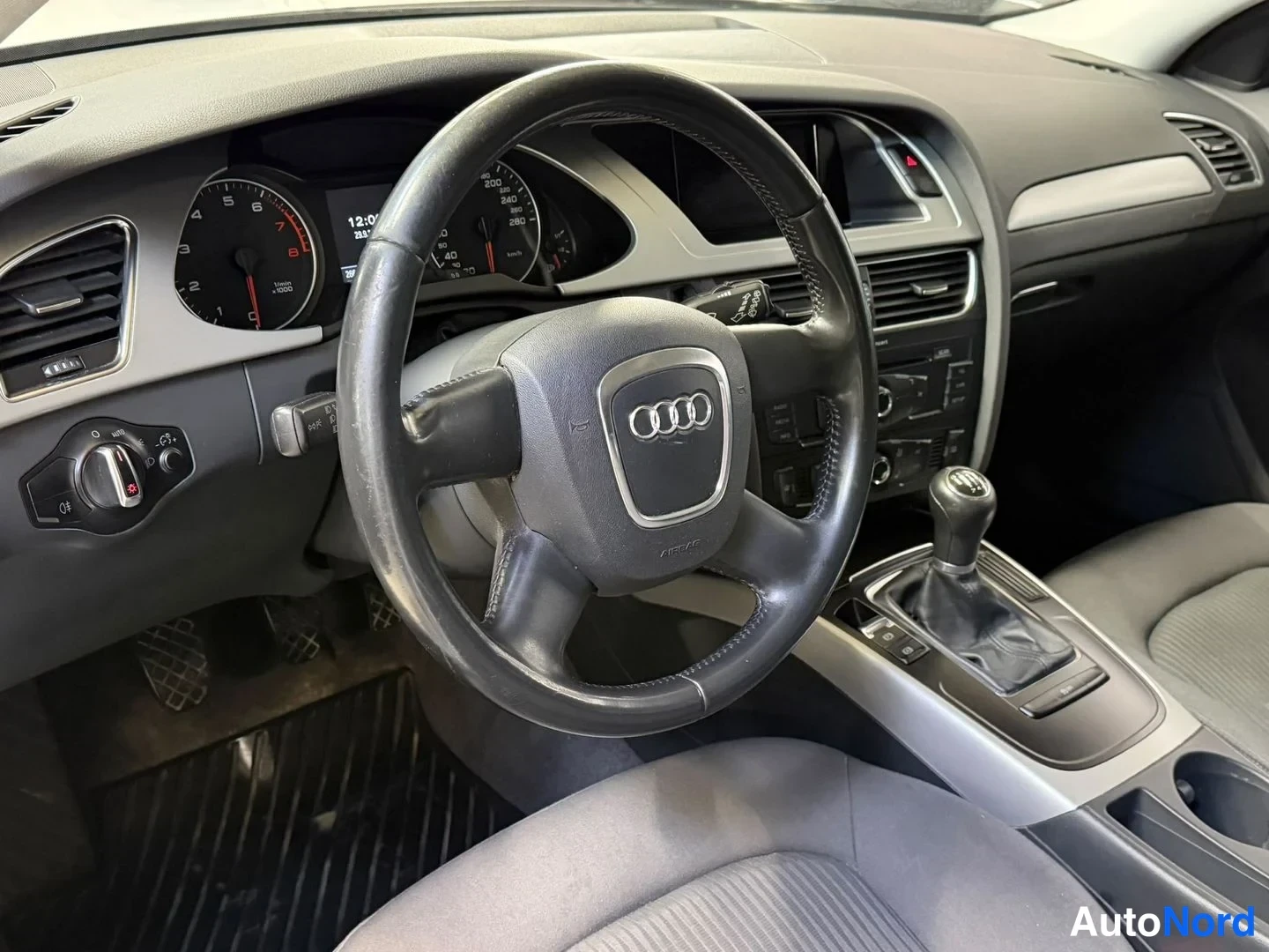 Sivulta: Kuljettajan puolen sisätilat: Audi-ohjauspyörä, kojelaudan mittaristo ja vaihtovipu näkyvät.
