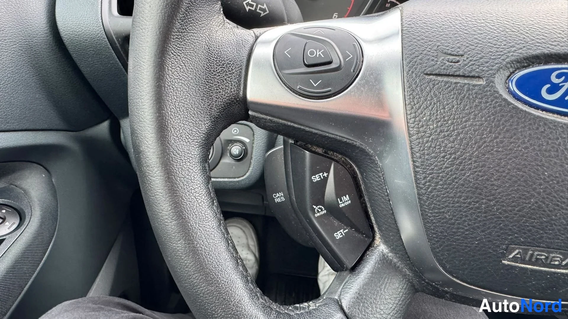 Muu: Ohjauspyörän oikea puoli: näkyvissä Ford-logo, OK-painikkeet ja vakionopeudensäädön (SET+, SET−, CAN RES) sekä nopeusrajoittimen (LIM ON/OFF) näppäimet.