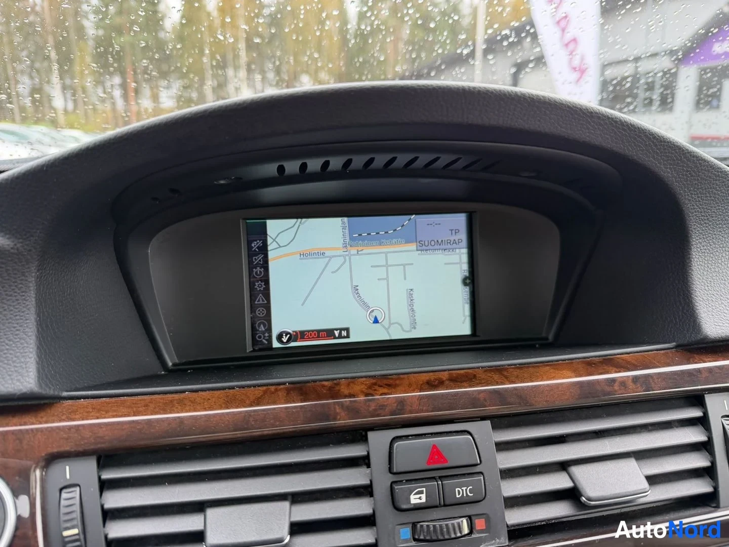 Yksityiskohta: Kojelaudan ylänäyttö näyttää navigaatiokarttaa tekstillä 'Holhintie' ja 'TP SUOMIRAP', alla varoitusvilkkupainike ja DTC-painike.