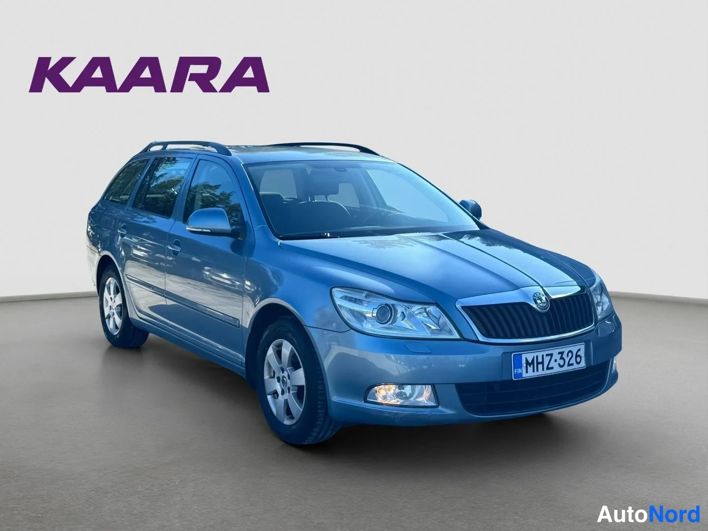 Etuviisto, nokka oikealle: Sininen harmansininen Skoda Octavia Combi -asema-auto kuvattu kolmeneljänneskulmasta edestä oikealle; etusäleikkö, ajovalot ja rekisterikilpi näkyvät.