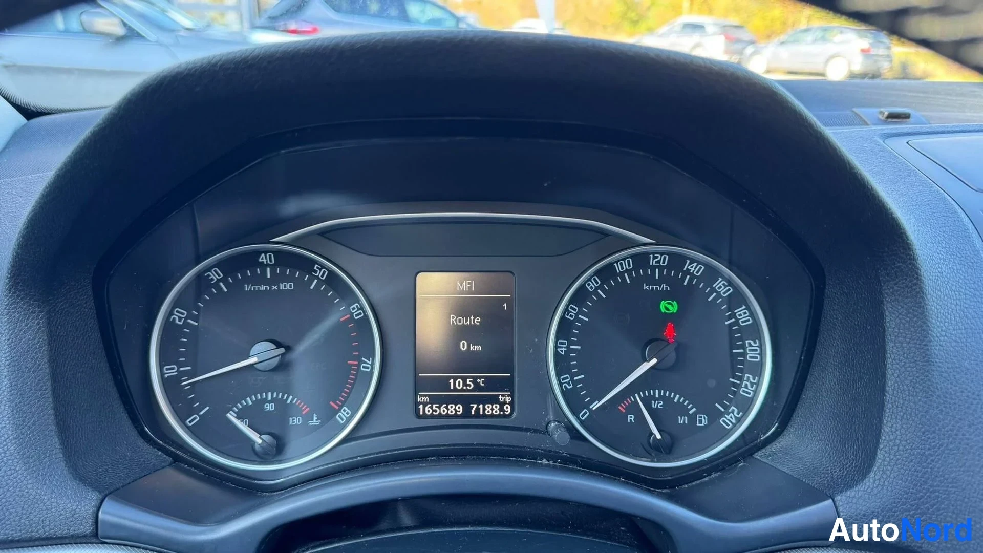 Edestä: Kojelaudan mittarit lähikuvassa: nopeusmittari asteikolla 0–220 km/h, kierrosmittari, näytössä teksti MFI, Route 0 km, lämpötila 10,5 °C ja matkamittari 165689