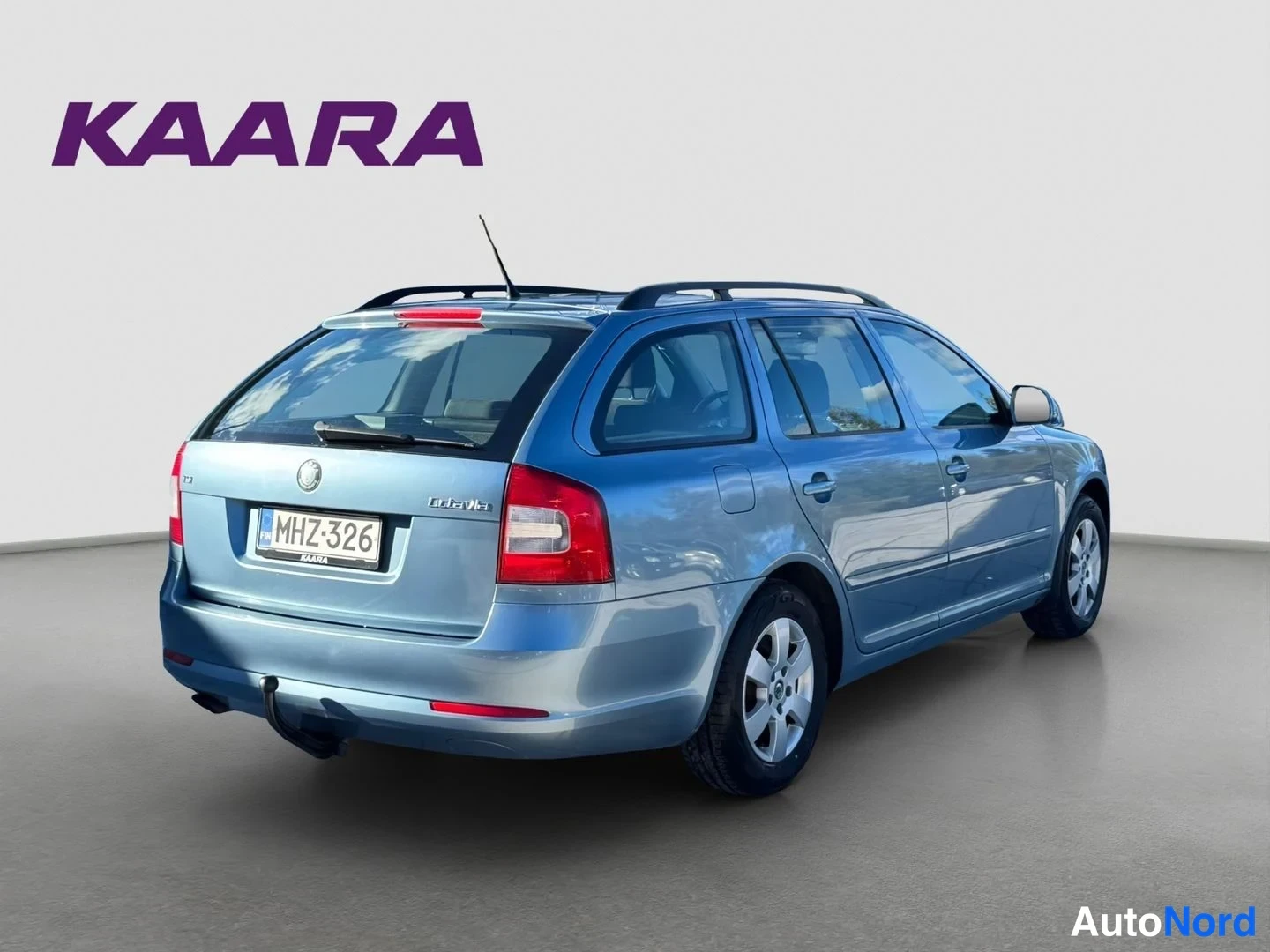 Takaviisto: Takakolmeneljänneskuv sinisestä harmansinisestä Skoda Octavia Combi -asema-autosta; takaosa, Octavia-tunnus, rekisterikilpi, kattokaiteet ja trukki ovat näkyvis