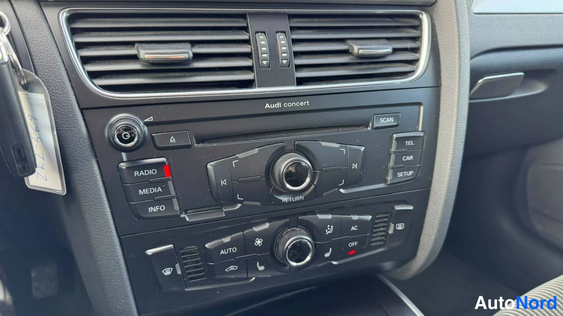 Yksityiskohta: Audi concert -radio ja automaattinen ilmastointi (AC, AUTO) kojelaudassa; painikkeita RADIO, MEDIA, INFO, TEL, CAR, SETUP.