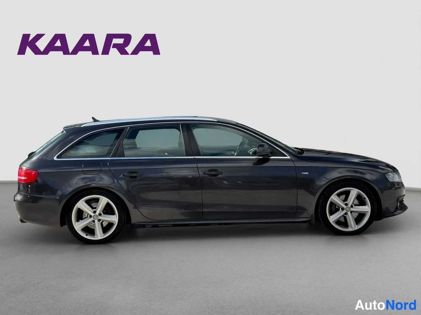Sivulta: Tummanharmaa Audi A4 Avant kylki oikealta studioteko­taustaa vasten.