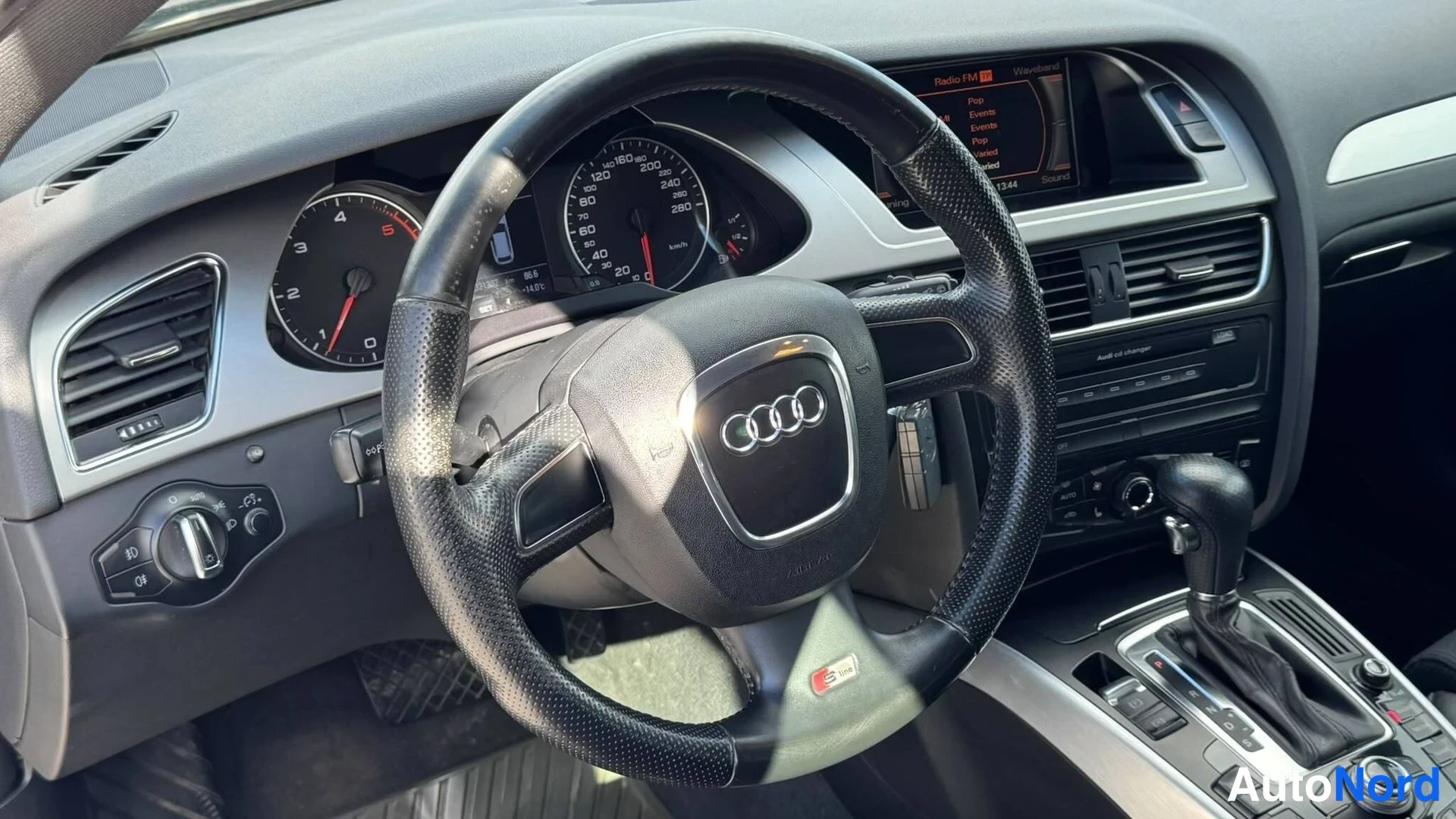 Muu: Audi A4:n ohjaamo edestä: neliohjainvolvalla varustettu ohjauspyörä, mittaristo, nesavigationäyttö ja automaattivaihteen valitsin.
