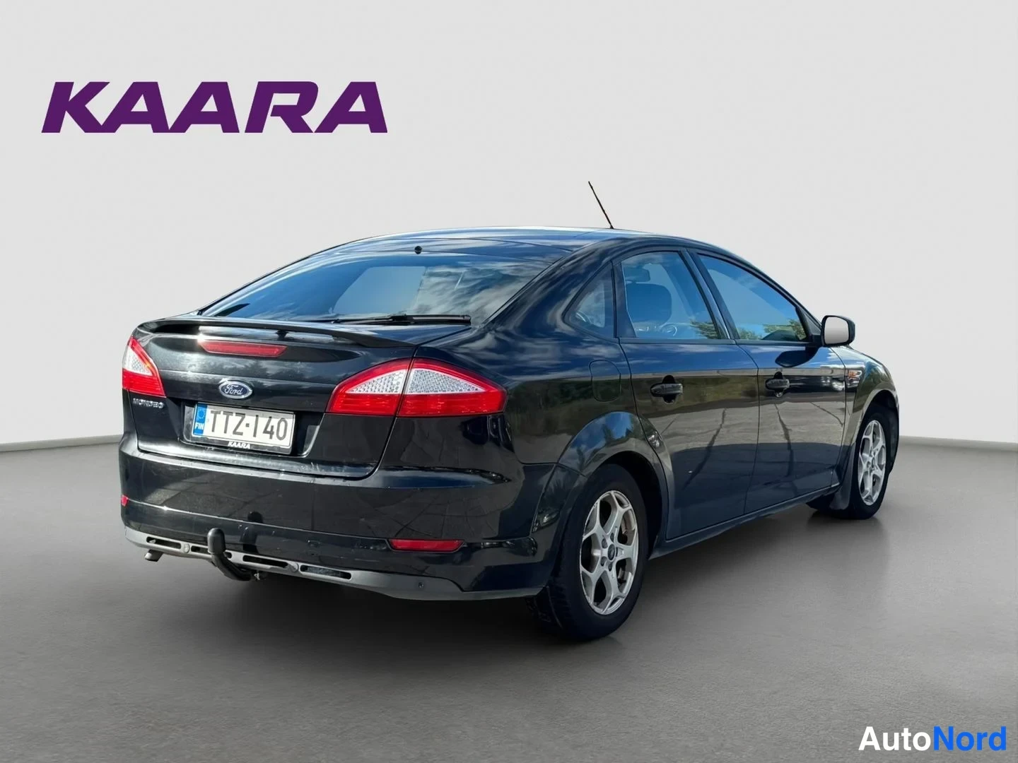 Takaviisto: Mustan Ford Mondeo -sedanin takakulma, rekisteritunnus, vetokoulu näkyvissä.